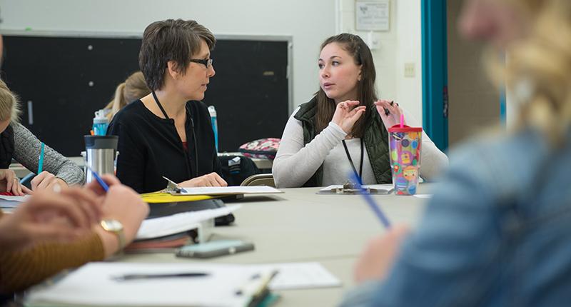 Two female students talking during a class.
